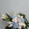 Box arrangement with roses, mums, hydrangeas, stocks, and calla lilies.