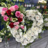 This touching heart-shaped arrangement is made primarily of white flowers, with a