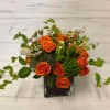 A beautiful arrangement of orange roses and mixed greens arranged in a