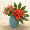This vibrant floral arrangement features a stunning mix of coral-orange amaryllis blooms