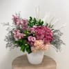 A luxurious arrangement of soft pink cymbidium orchids, mauve rose, hydrangeas, and