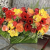 Gorgeous mixture of fall colored blooms in sophisticated glass leaf lined vase