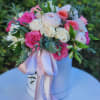 The arrangement in white hatbox features a stunning mix of flowers, including