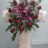 Cross with red roses, white carnations, and lilies. 