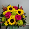 Container arrangement with sunflowers, mums, roses, and cushion daisies.