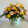 A modern and bright box with pincushion roses, ranunculus, spray roses, gerbera