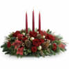 A beautiful Christmas centerpiece filled with Christmas greens red florals red candles