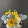 Yellow, white, and blue flowers in an adorable baby elephant container to