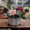 This romantic arrangement features soft blush roses, deep red ranunculus, and lush