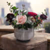 This romantic arrangement features soft blush roses, deep red ranunculus, and lush