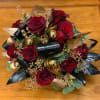 Gorgeous winter arrangement with red roses, tropical leaves, gold seeded eucalyptus, gold