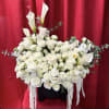 An elegant vase arrangement featuring pristine white calla lilies, classic white roses
