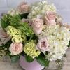Cylinder vase wrapped with pink ribbon, filled with hydrangeas and a dozen