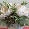 This elegant arrangement features soft ivory artificial roses surrounded by lush greenery