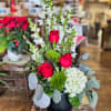 Stylized, three sided floral arrangement featuring roses, snap dragons and hydrangea in