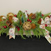 A long and low arrangement of mixed evergreen, accented with deep red