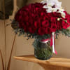 A striking arrangement of rich red roses with a delicate orchid gracefully