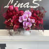 An arrangement featuring pink roses and purple Phalaenopsis orchids is a stunning