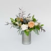 Woodsy floral arrangement including seasonal blooms and foliage in a tin vase.