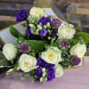 A vibrant mix of deep purple lisianthus, creamy white roses, and pops