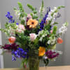A vase filled with blue delphinium, stock snap dragons and roses of