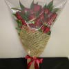 Red roses and red spray roses wrapped in a timeless presentation style.