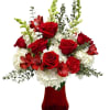 The vase is filled with vibrant red roses, elegant alstroemerias, striking snapdragons