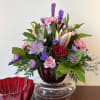 This stunning arrangement of seasonal blooms including roses and lilies is presented
