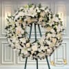 Beautiful sympathy wreath of white roses, lilies, mums and carnations. Accented by