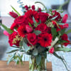 This striking all-red flower arrangement features vibrant red gerbera daisies, roses, and