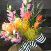 This vibrant flower arrangement features a stunning mix of orange tulips, soft