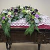 Elevate your memorial tribute with our stunning floral arrangement, featuring rich purple