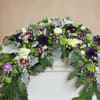 Elevate your memorial tribute with our stunning floral arrangement, featuring rich purple