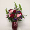 Red swirl vase is arranged red roses, pink carnations, pink miniature carnations