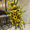 Yellow roses, yellow sunflowers, bells of Ireland, and greenery.