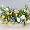 Blue delphinium, yellow spray rose, white tulips and lisianthus come together to