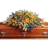 Full of light and love, this colorful casket spray celebrates a bright