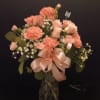 Assorted pink flowers arranged in a glass vase