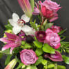 This vase arrangement is made up of lilies, roses, orchids, and calla