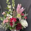 Beautiful reds and pinks in this arrangement of lilies, roses, larkspur, hyacinth