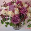 Lovely Lavender and pure White roses are arranged in clear glass vase
