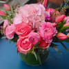 A mix of vibrant pink roses,tulips,ranunculus with a variety of greens in
