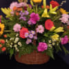 The large basket arrangement  is full of assorted flowers 
such as