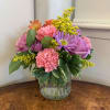 Lavender roses, pale pink carnations, lavender daisies, orange alstroemeria and solidago arranged