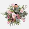 A handcrafted bouquet of blush pink roses, calla lilies, lisianthis, and protea