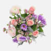 Blush ranunculus, pink roses, purple lisianthus, and wax flowers are paired with
