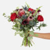 Red garden roses, black calla lilies, purple snapdragons, and pink ice protea