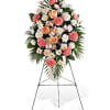 Standing spray with pink carnations, white chrysanthemums and roses on an easel.