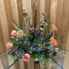 This arrangement is a rustic, hunter-themed floral design. It features natural and