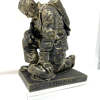 A handsomely detailed bronze finish figurine. It depicts a firefighter dressed for